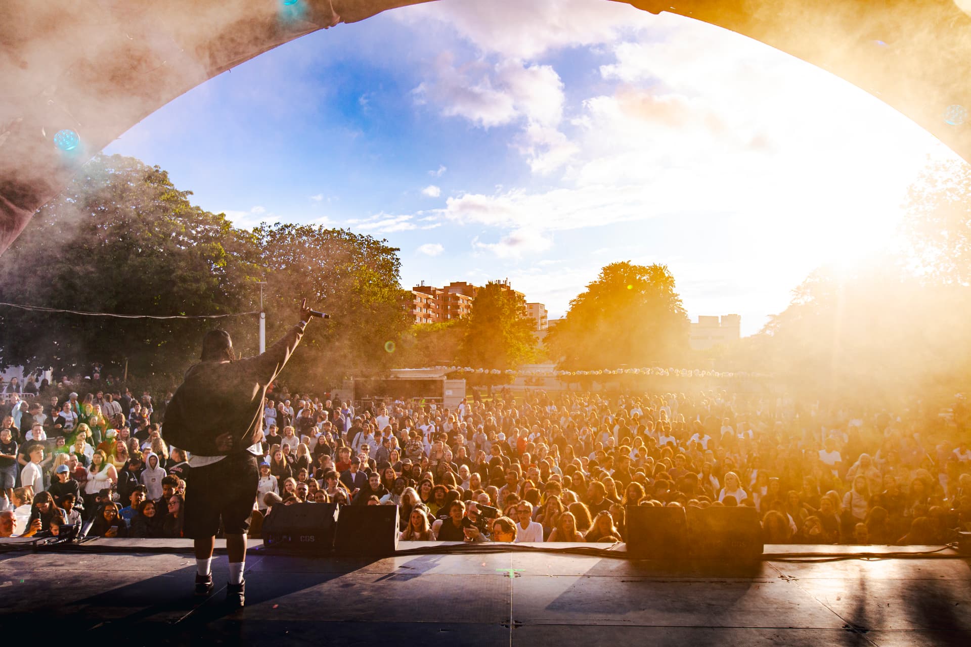 Dancer on the outdoor stage facing thousands in the crowd at golden hour